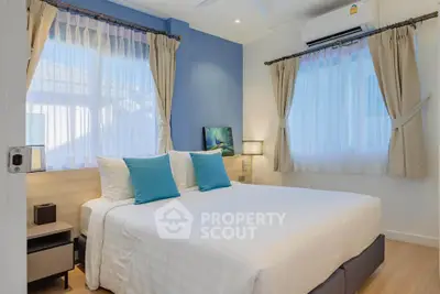Charming bedroom with blue accent wall and natural light, featuring cozy bedding and modern decor.