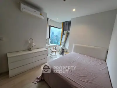 Spacious bedroom with city view, modern furniture, and natural light.