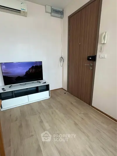 Modern living room with sleek TV setup and wooden flooring, perfect for cozy entertainment.