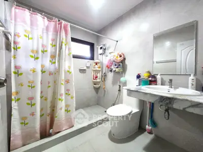 Spacious bathroom with floral shower curtain and modern fixtures in a bright, tiled setting.