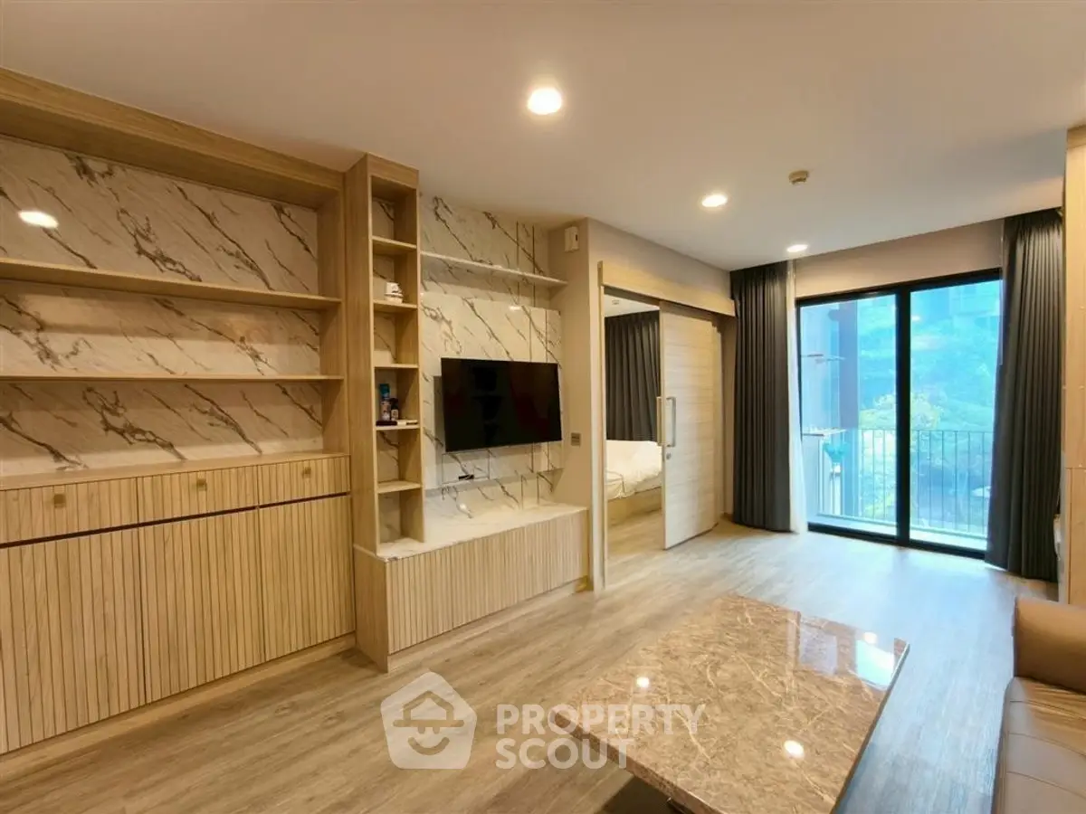 Modern living room with marble accents and large window leading to balcony, showcasing elegant interior design.