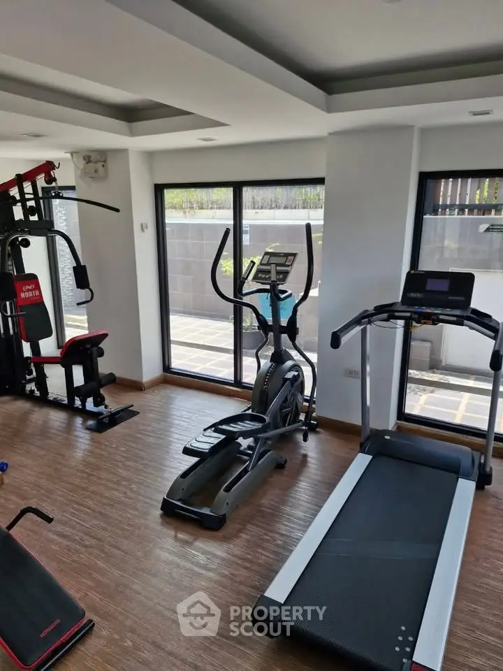 Modern gym with state-of-the-art equipment and large windows for natural light.