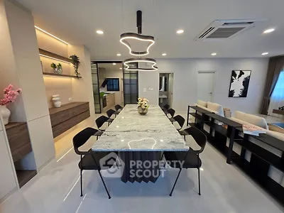 Modern open-plan living and dining area with stylish lighting and elegant decor.
