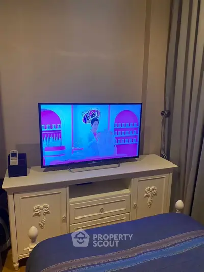 Cozy bedroom with elegant white TV stand and flat-screen TV, perfect for relaxation and entertainment.