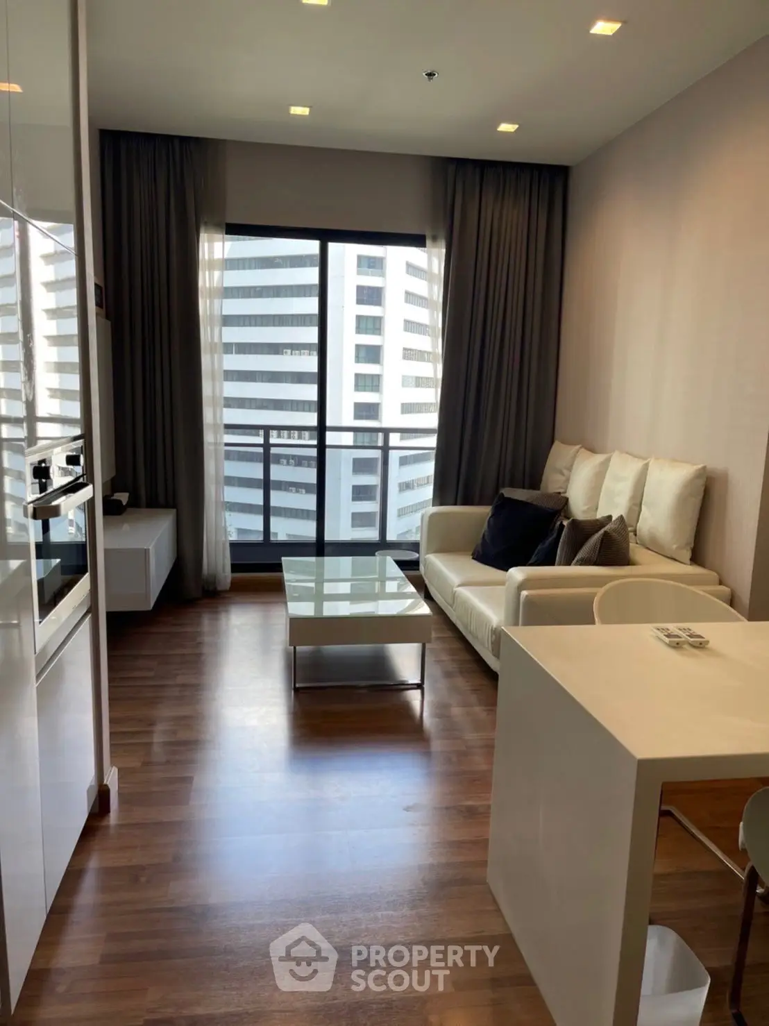 Modern living room with city view, featuring sleek furniture and large windows for natural light.