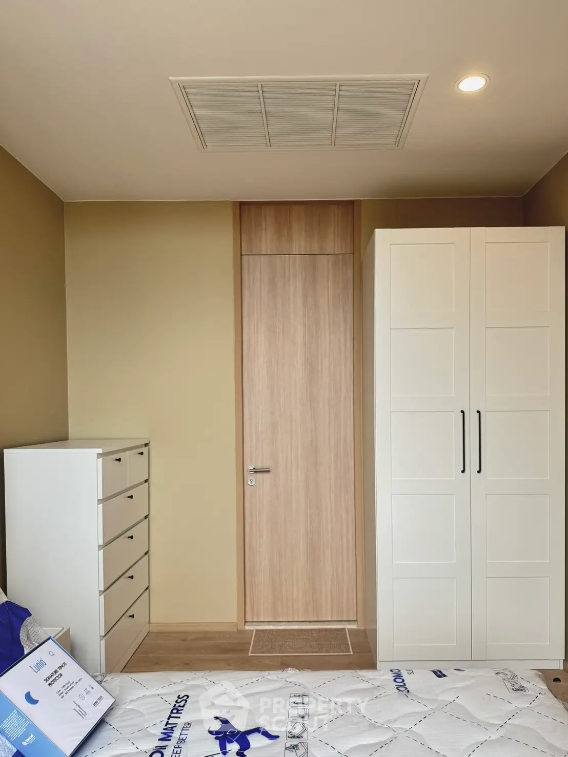Modern bedroom with sleek wardrobe and chest of drawers, featuring minimalist design and warm tones.