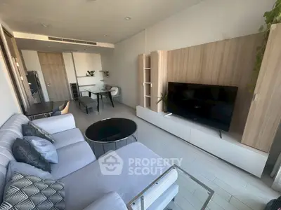 Modern living room with sleek furniture and large TV, open layout to dining area, stylish decor.
