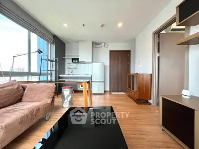 Modern living room with open kitchen, large windows, and stylish furniture in a high-rise apartment.
