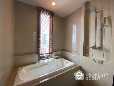 Modern bathroom with sleek bathtub and shower, featuring elegant window blinds.