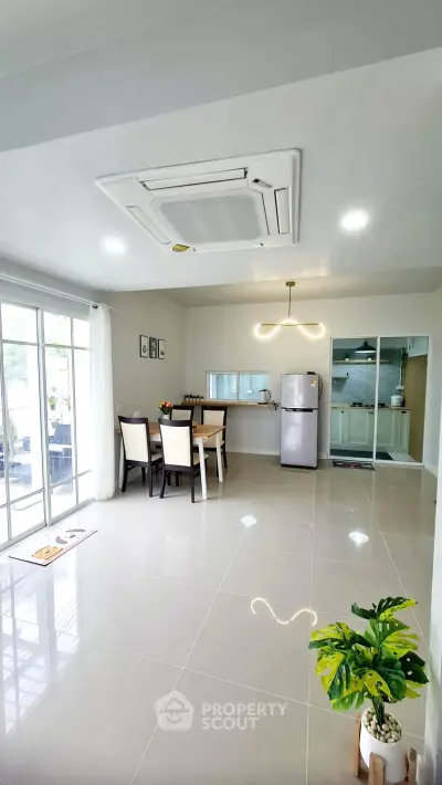 Spacious modern living room with dining area and sleek kitchen, featuring large windows and elegant lighting.