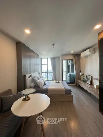 Modern bedroom with stylish decor and large window offering city views