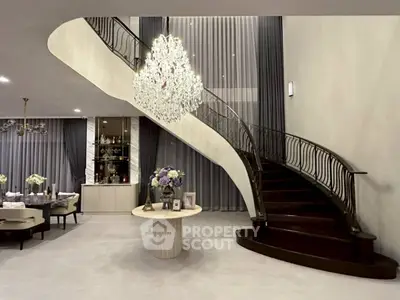 Luxurious living room with elegant staircase and chandelier, perfect for upscale living.