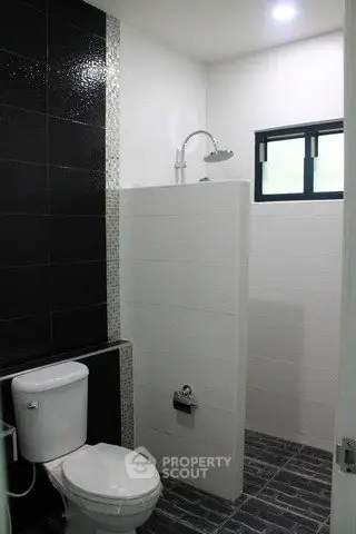Modern bathroom with sleek black and white tiles and a compact shower area.