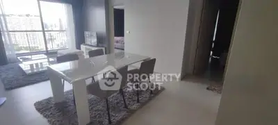 Modern dining area with sleek table and chairs, open to living room with city view.