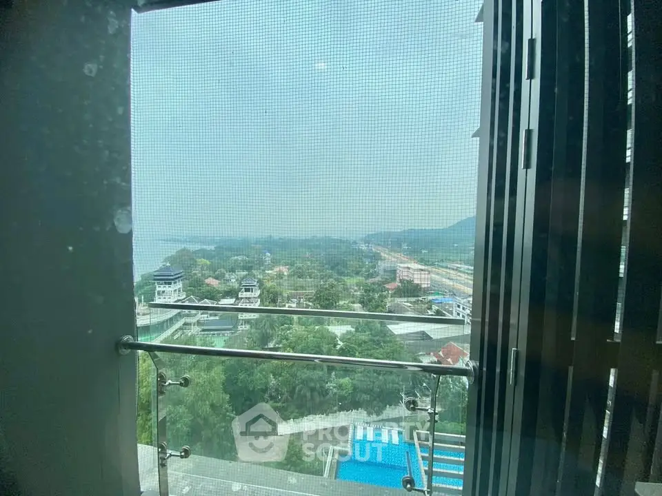Stunning high-rise balcony view overlooking lush greenery and distant hills, perfect for serene living.