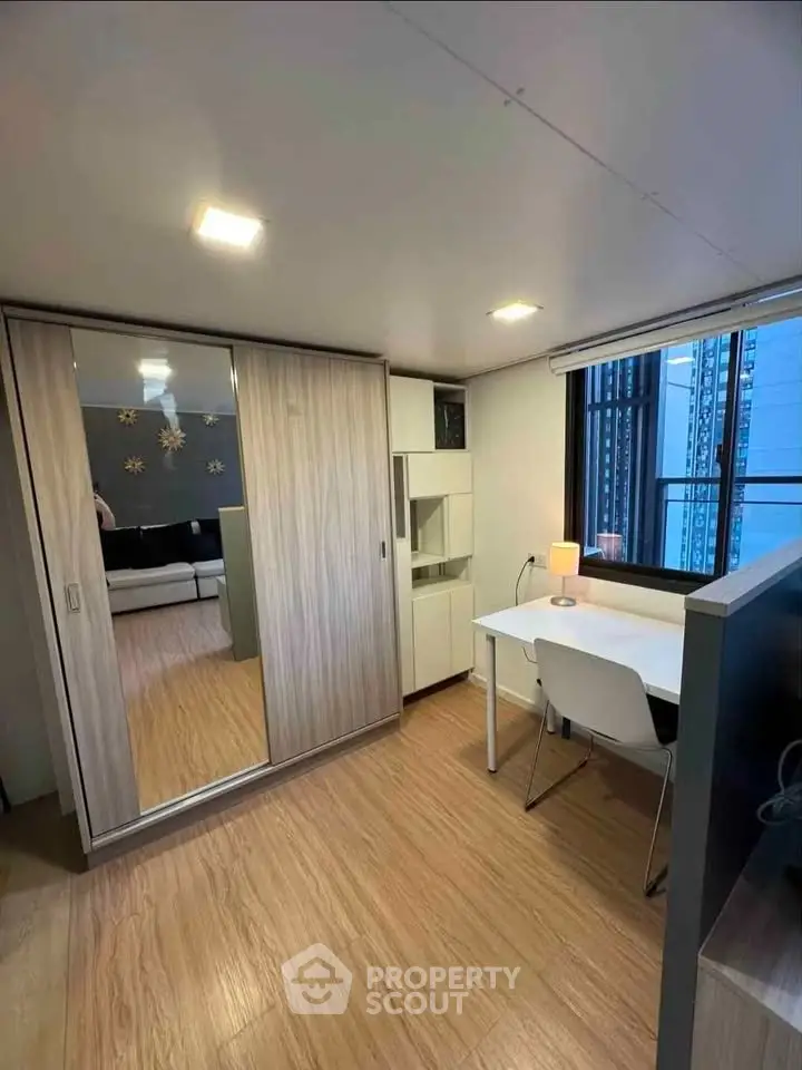 Modern study room with sleek desk, chair, and mirrored wardrobe in a bright apartment.