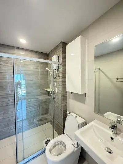Modern bathroom with glass shower, sleek fixtures, and neutral tiles.