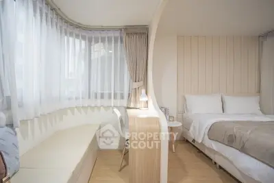 Modern bedroom with stylish partition and cozy seating area, featuring elegant decor and natural light.