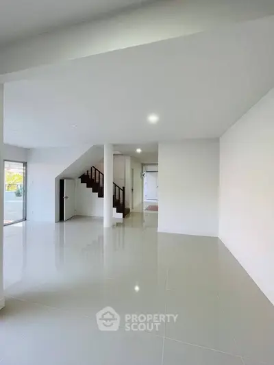 Spacious modern living room with glossy tile flooring and staircase