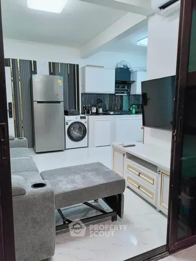 Modern open-layout living room with kitchen, featuring sleek appliances and stylish decor.