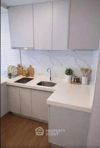 Modern kitchen with sleek cabinetry and marble backsplash, featuring an induction cooktop and minimalist design.