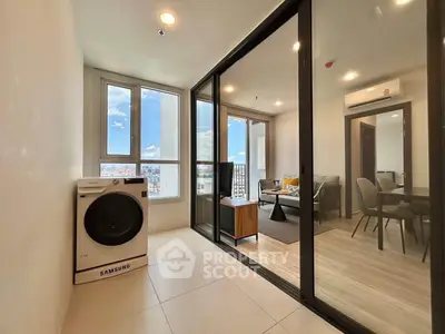 Modern apartment with glass partition, featuring a cozy living room and in-unit washing machine.