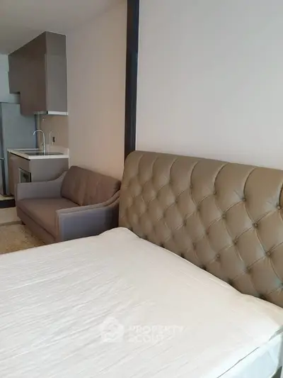 Modern studio apartment with cozy bed and compact kitchen area, perfect for urban living.