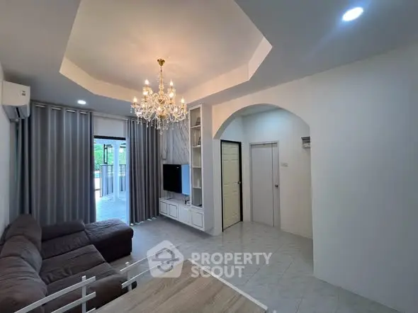 Elegant living room with chandelier and balcony access in modern apartment