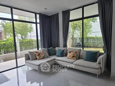 Spacious living room with modern sofa and large windows overlooking garden