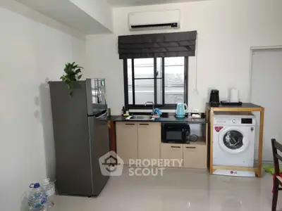 Modern kitchen with appliances including fridge, microwave, and washing machine in compact layout.