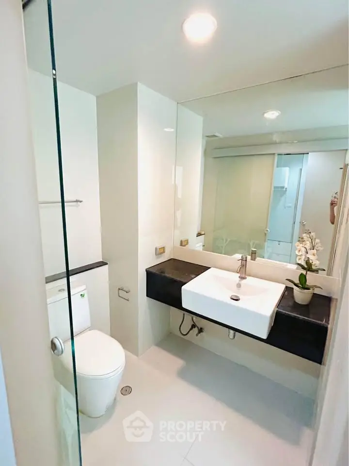 Modern bathroom with sleek design, featuring a glass shower and elegant fixtures.