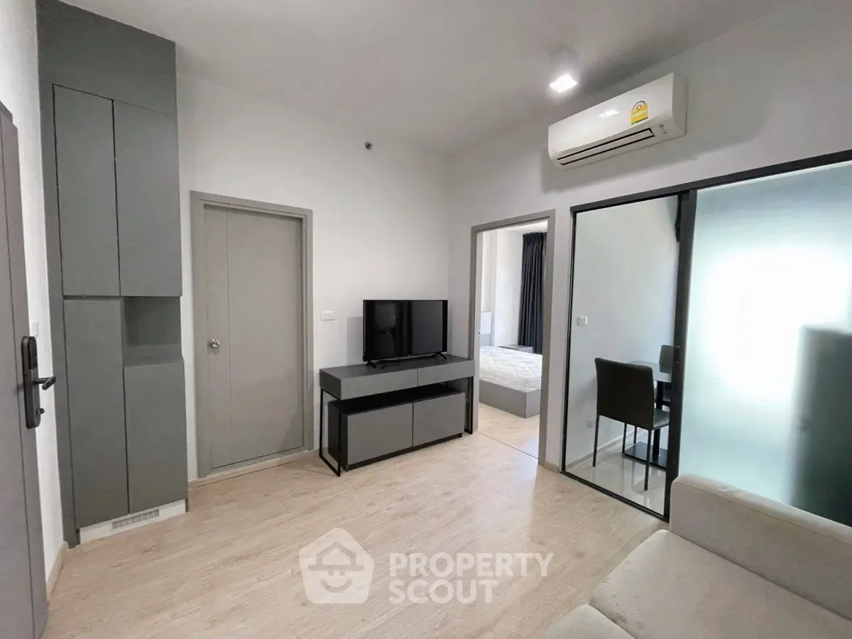 Modern living room with sleek design and air conditioning, featuring a TV and stylish furniture.