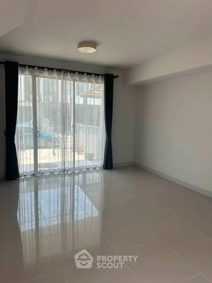 Spacious living room with large windows and elegant curtains, perfect for natural light and modern living.