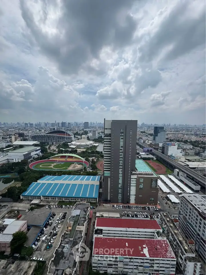 Stunning cityscape view from high-rise building showcasing urban skyline and sports complex.