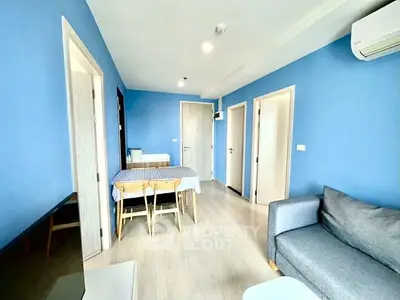 Modern living room with blue walls, cozy sofa, and dining area