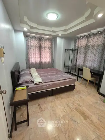 Spacious bedroom with modern ceiling design and natural light
