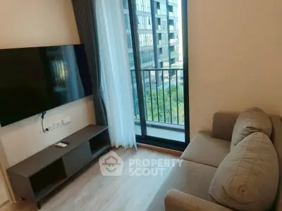 Modern living room with sleek TV setup and balcony view in urban apartment.