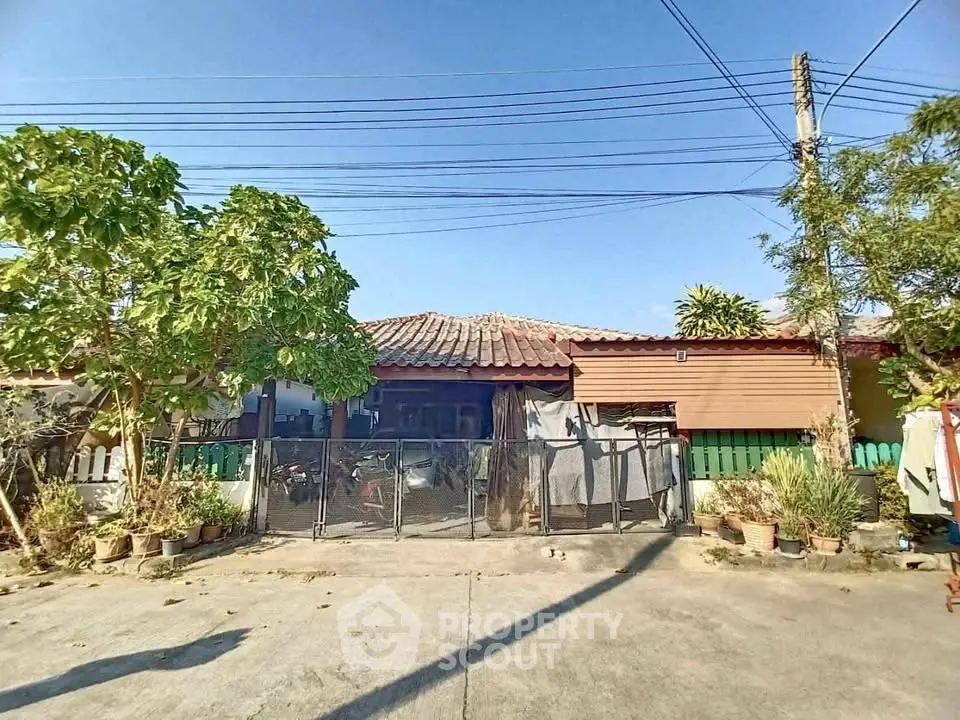 Charming single-story home with rustic roof and lush greenery in a peaceful neighborhood.