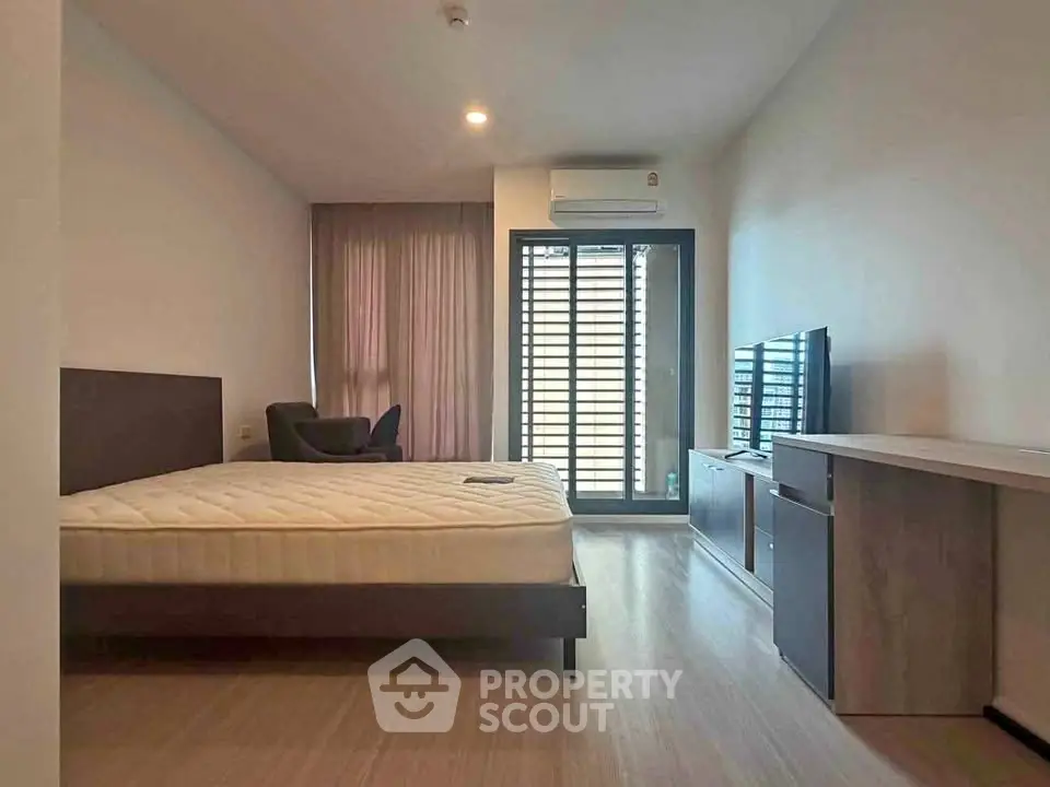 Modern bedroom with large window and sleek furniture in a stylish apartment.