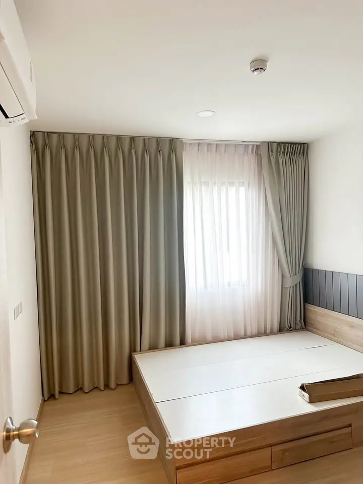 Spacious bedroom with elegant curtains and modern wooden bed frame, perfect for cozy living.