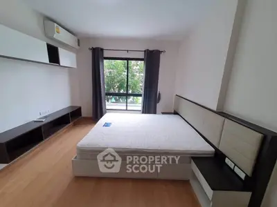 Spacious bedroom with large window and modern furnishings in a stylish apartment.