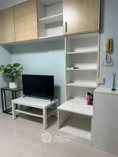 Modern living room with sleek TV stand, open shelving, and stylish decor in a cozy apartment.