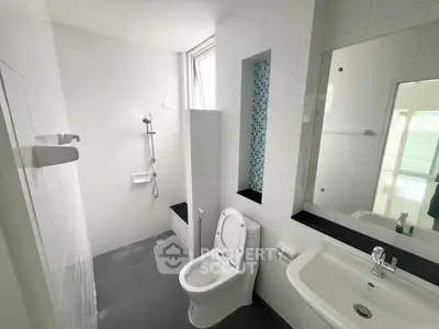 Modern bathroom with sleek design, featuring a shower and toilet in a bright, tiled space.