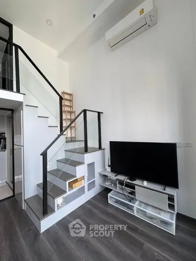 Modern loft-style living room with sleek staircase and wall-mounted TV, perfect for urban living.