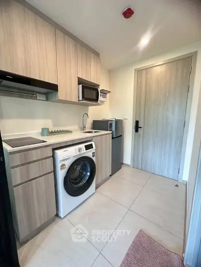 Modern compact kitchen with washing machine and microwave in stylish apartment