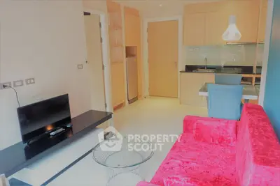 Modern living room with vibrant red sofa and sleek kitchen area in open layout apartment.