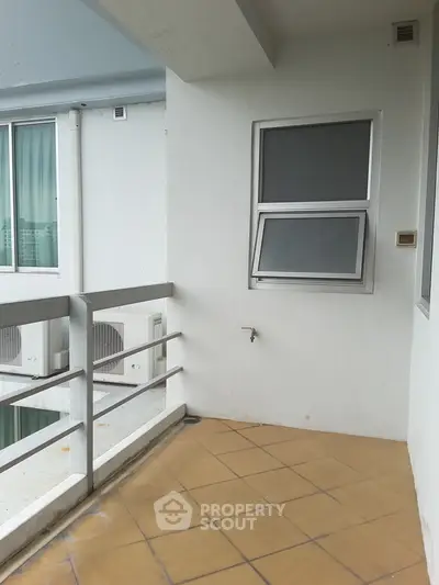 Spacious balcony with tiled flooring and modern railing in a contemporary apartment.