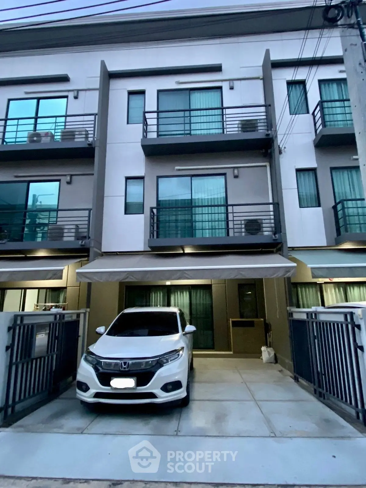 Modern townhouse exterior with gated parking and balcony views.