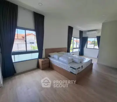 Spacious bedroom with large windows and modern furnishings, ideal for natural light lovers.