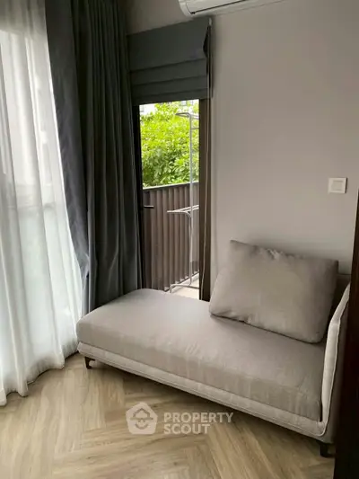 Cozy corner with a stylish chaise lounge and balcony view, perfect for relaxation.